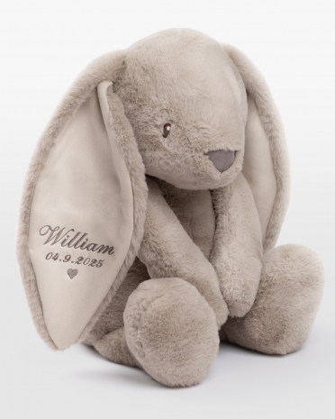 hiekanvärinen pehmopupu, jossa on kirjailtu nimi ja syntymäpäivä