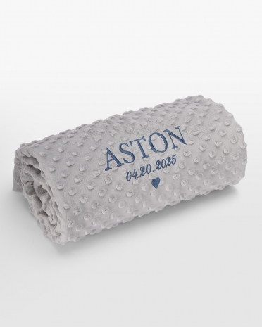 Harmaa vauvanpeitto sinisellä nimikirjonnalla