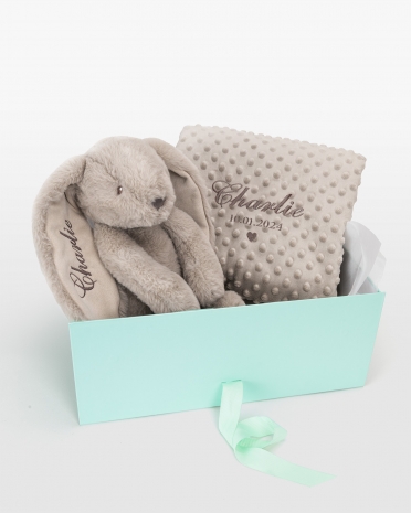 Lahjapaketti, joka sisältää pehmolelun ja vauvanpeiton, johon brodyyritään nimi.