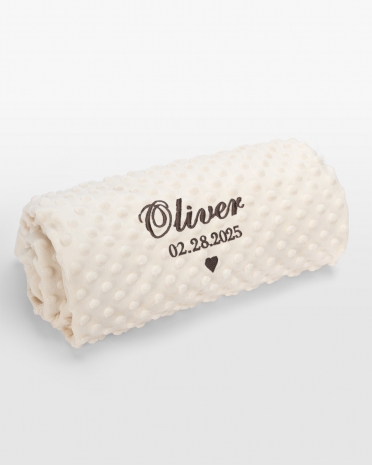 Kermanvärinen vauvanpeitto ruskealla brodeerauksella