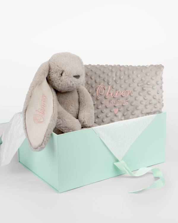 Lahjapaketti, joka sisältää pehmolelun ja vauvanpeiton, johon brodyyritään nimi.