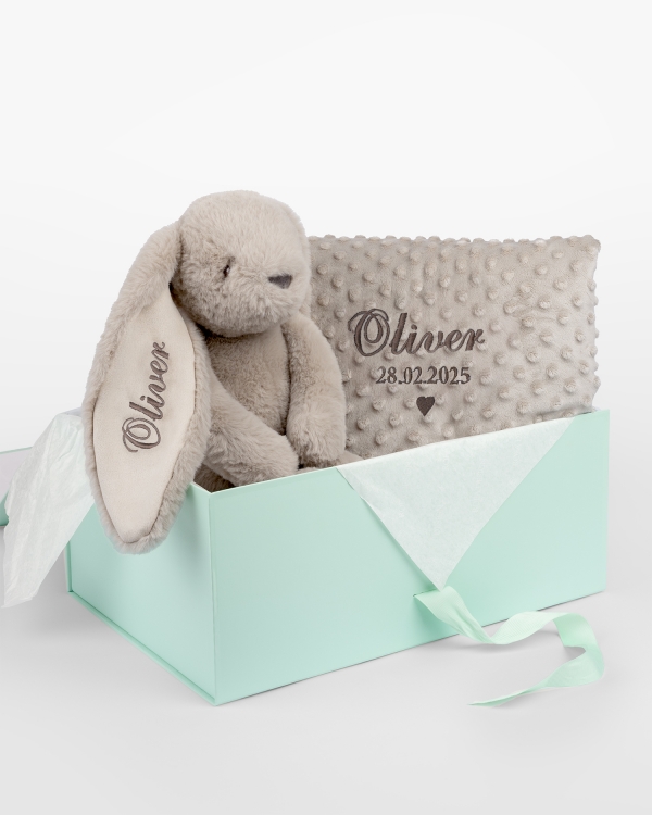 Lahjapaketti, joka sisältää pehmolelun ja vauvanpeiton, johon brodyyritään nimi.