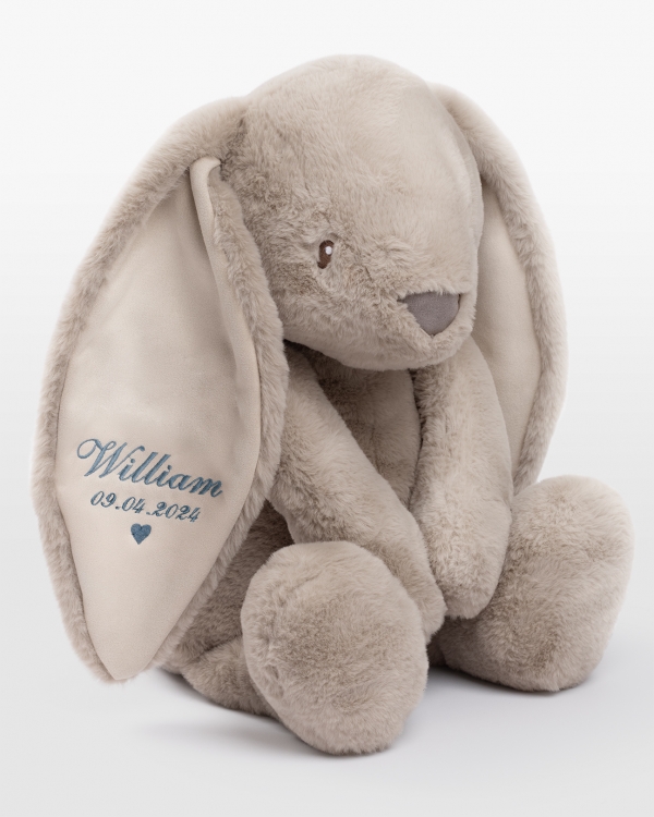 Hiekanvärinen iso pupu pehmolelu henkilökohtaisella sinisellä kirjonnalla korvassa.