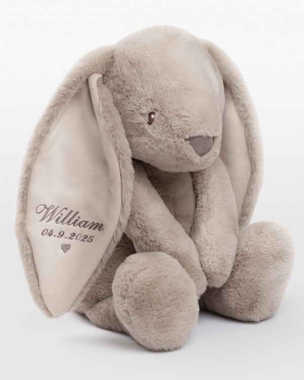 hiekanvärinen pehmopupu, jossa on kirjailtu nimi ja syntymäpäivä