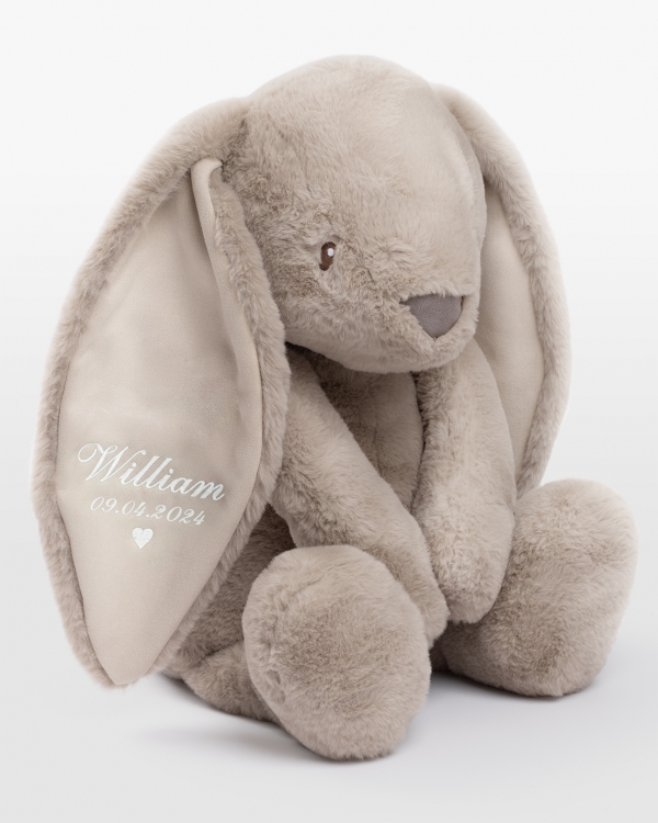 Hiekanvärinen iso pupu pehmolelu henkilökohtaisella valkoisella kirjonnalla korvassa.