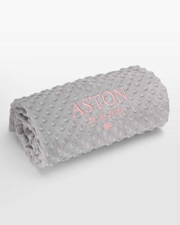 Harmaa vauvanpeitto nimellä vaaleanpunaisella brodeerauksella