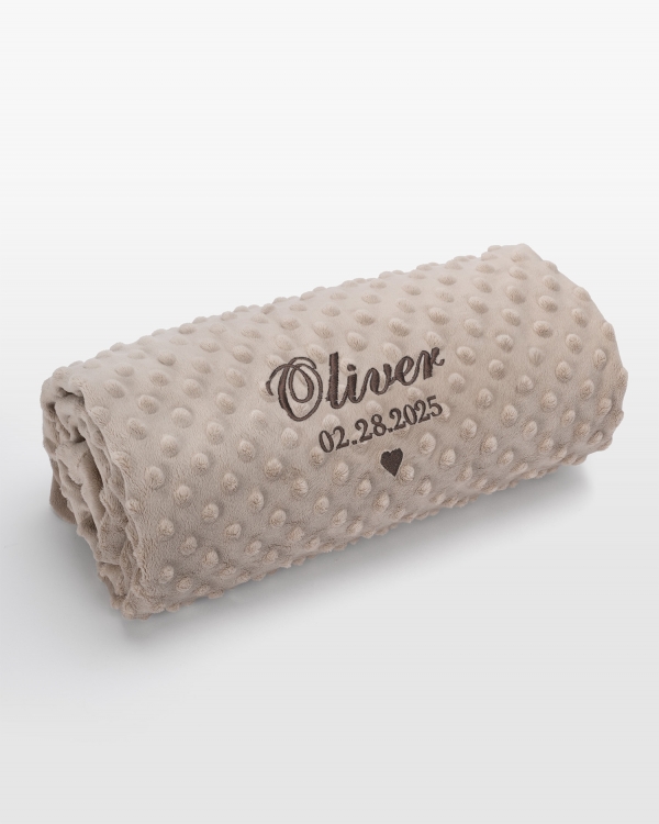 Hiekanvärinen vauvanpeitto ruskealla nimikirjonnalla