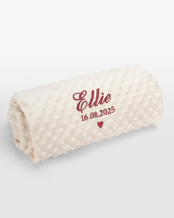 Kermanvärinen vauvanpeitto tummanpunaisella brodeerauksella