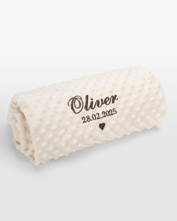 Kermanvärinen vauvanpeitto ruskealla brodeerauksella