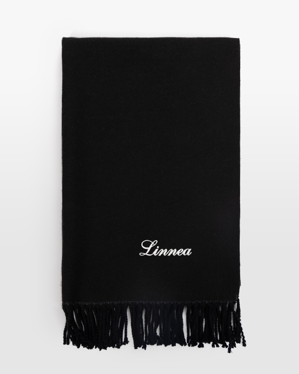 Musta kaulahuivi henkilökohtaisella valkoisella kirjonnalla, ihanteellinen kontrastikkaaseen tyyliin ja mukavaan talviin.