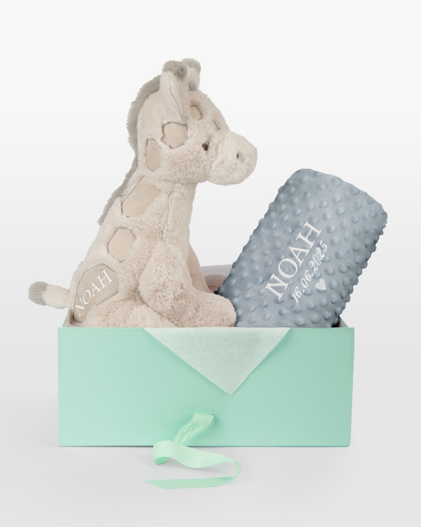 Pehmolelu ja sininen peitto, jossa kirjailtu nimi ja päivämäärä