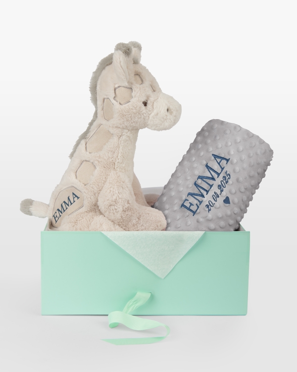 Pehmolelu ja harmaa viltti, jossa kirjailtu nimi ja päivämäärä