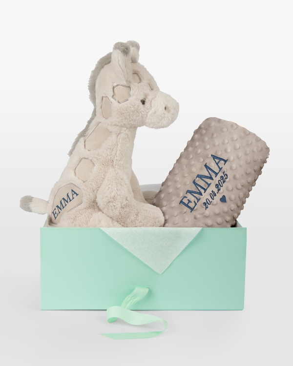 Pehmolelu ja ruskea peitto, jossa kirjailtu nimi ja päivämäärä