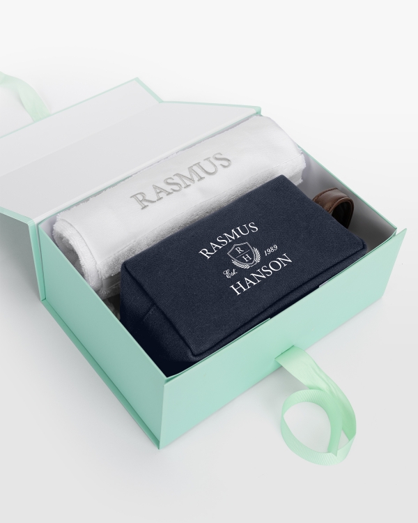 Valkoinen pyyhesetti (50x70) hopeisella kirjonnalla ja tummansininen kangasnecessär nimipainatuksella, täydellinen tyylikkääseen