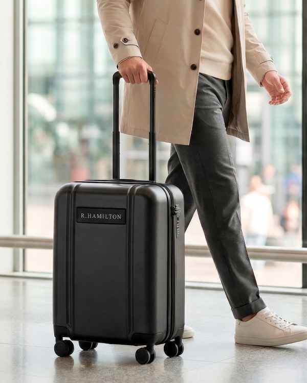 Tummanharmaa lentolaukku, jossa on kaiverrettu nimi - täydellinen matkalle