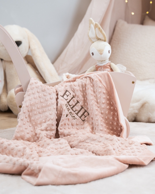 Mukava vaaleanpunainen viltti, jossa on kirjailtu nimi ja päivämäärä lastenhuoneeseen