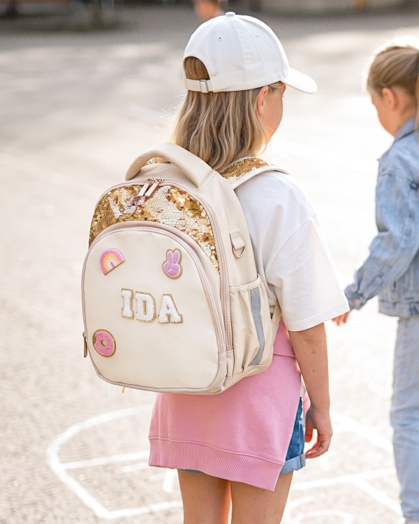 Beige reppu, jossa on paljon käytännöllisiä lokeroita kouluun