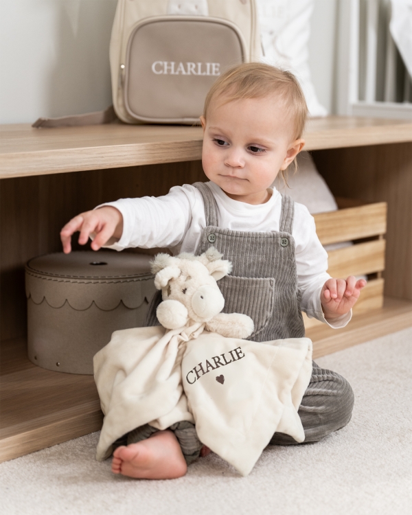 Uniriepu kirahvin muodossa, jossa ruskealla kirjailtu nimi