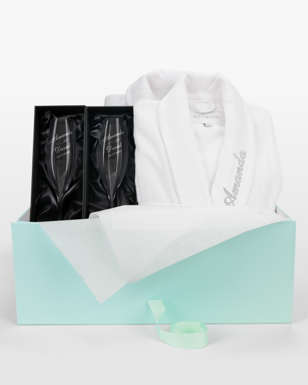 Hääpäivälahjasetti, jossa on kaksi nimikoitua kylpytakkia ja kaksi kaiverrettua samppanjalasia