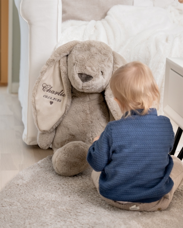 suuri pehmolelu, johon on kirjailtu nimi ja päivämäärä